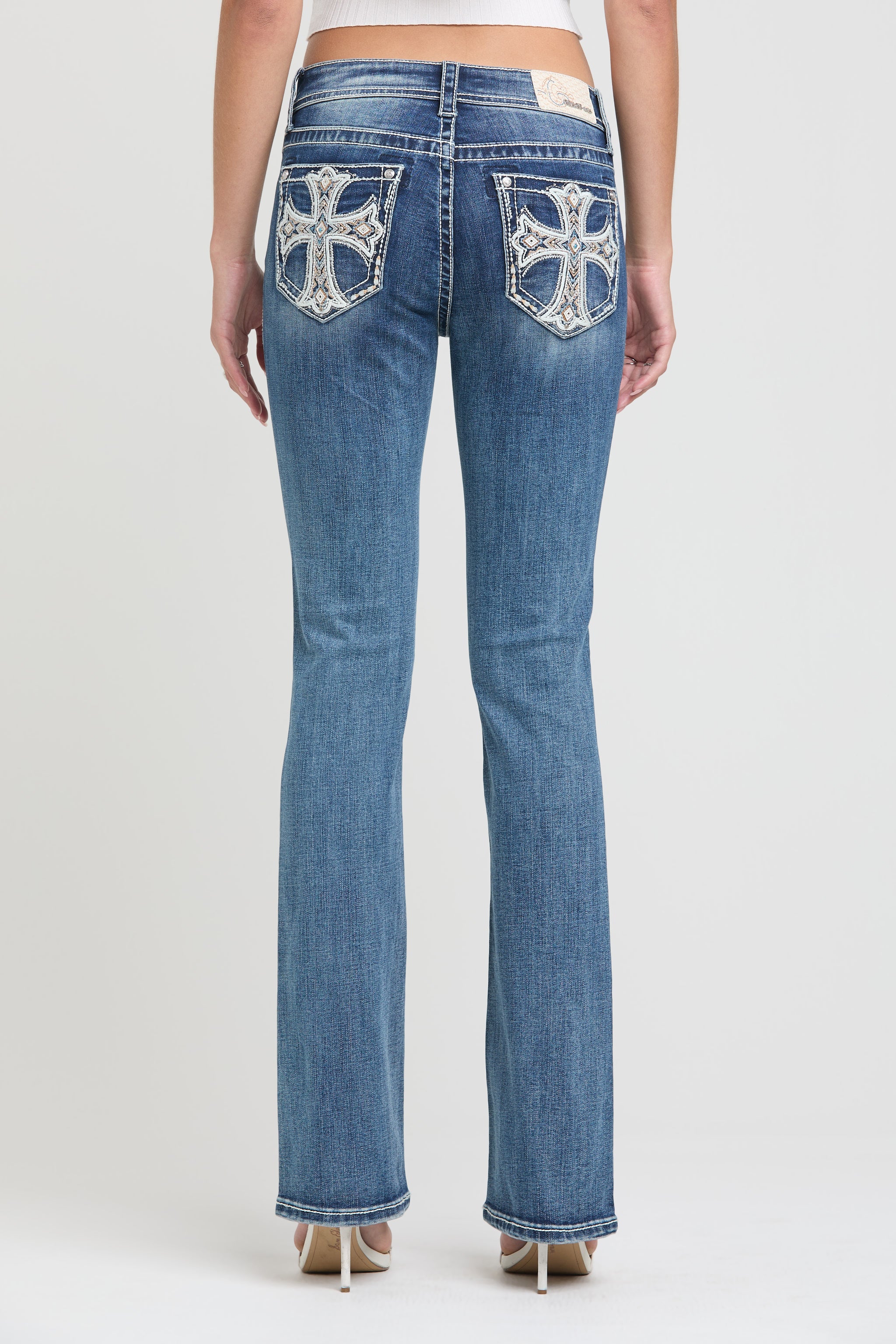 Grace in LA womens bootcut jeans in a medium featuring a full rear view with symmetrical crystal-embellished cross embroidery on both back pockets.