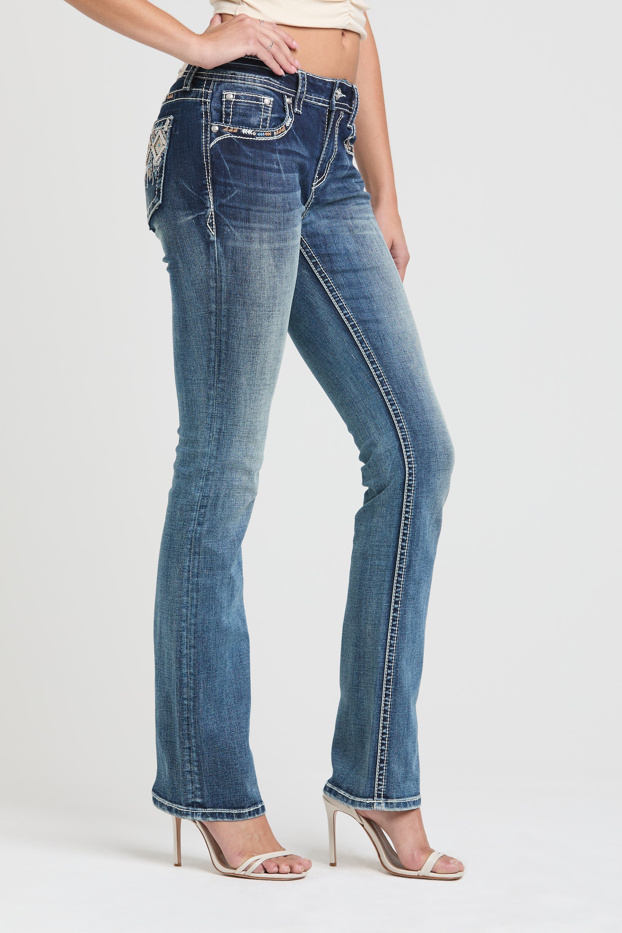Grace in LA rhinestone jeans for women in a medium wash featuring a multi-layered geometric tribal embroidery design on the back pocket and yoke.