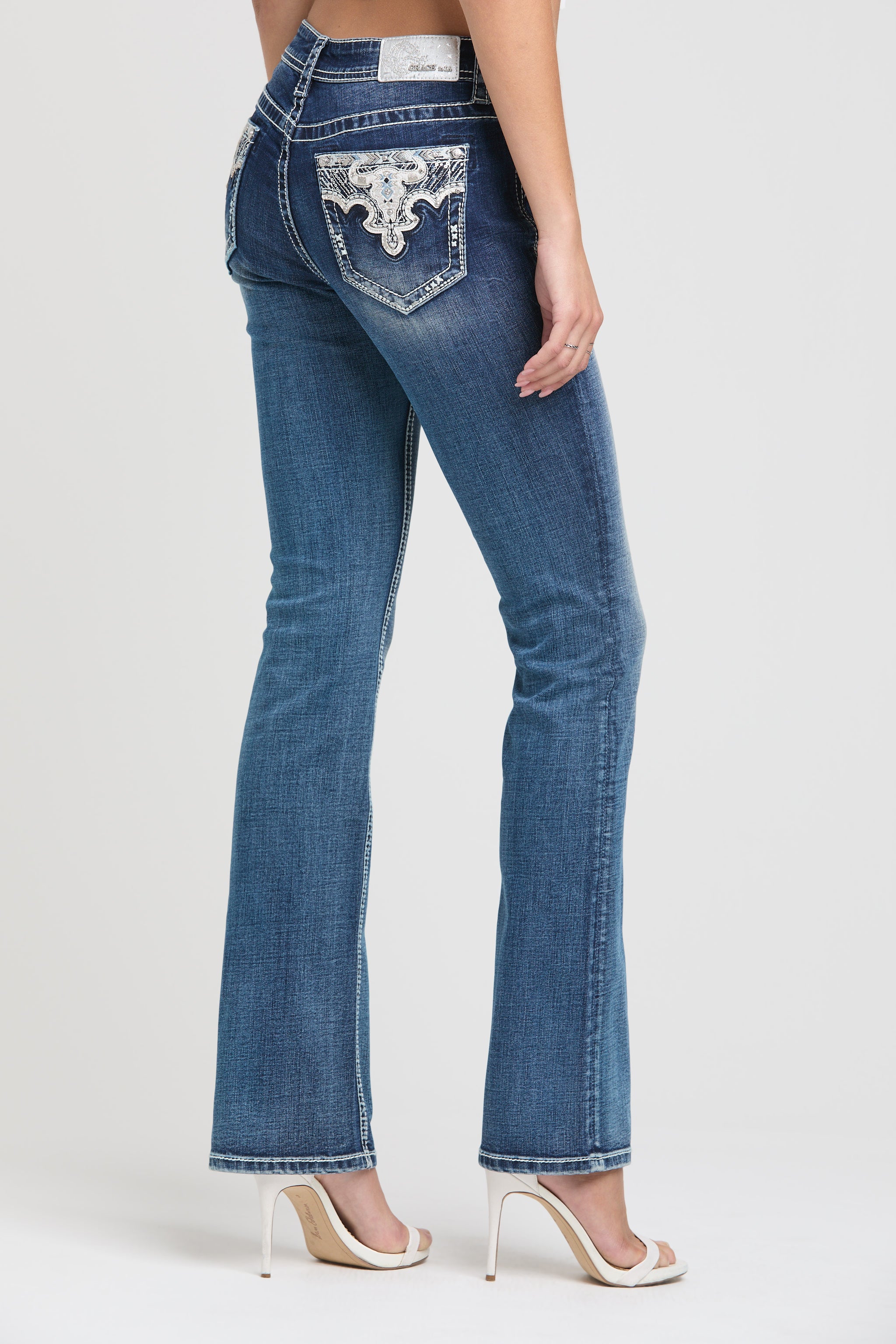 Grace in LA womens bootcut jeans in a dark featuring western-inspired white lace embroidery and rhinestone embellishments on the back pockets.
