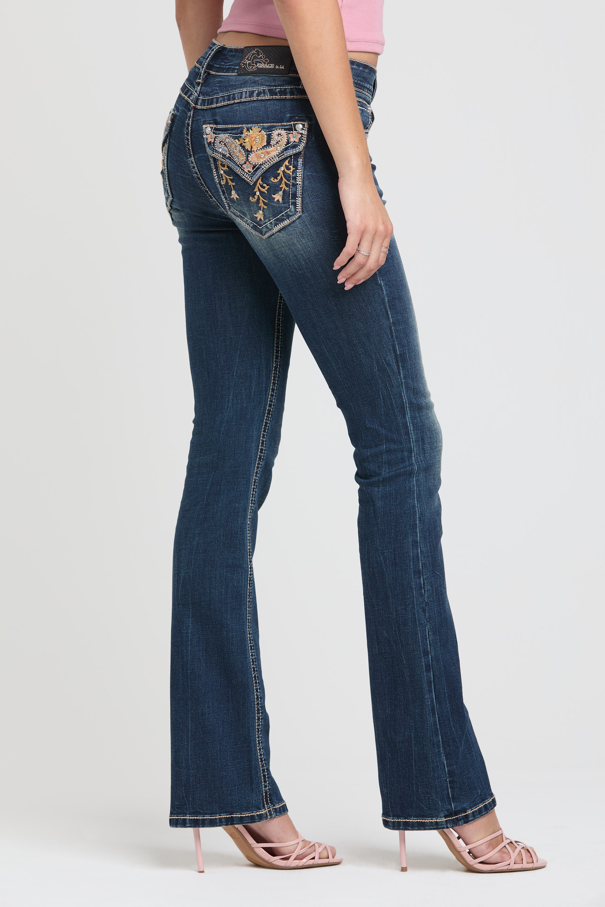Full straight-on rear view of Grace in LA womens bootcut jeans showing symmetrical colorful paisley and floral vine pocket embroidery.