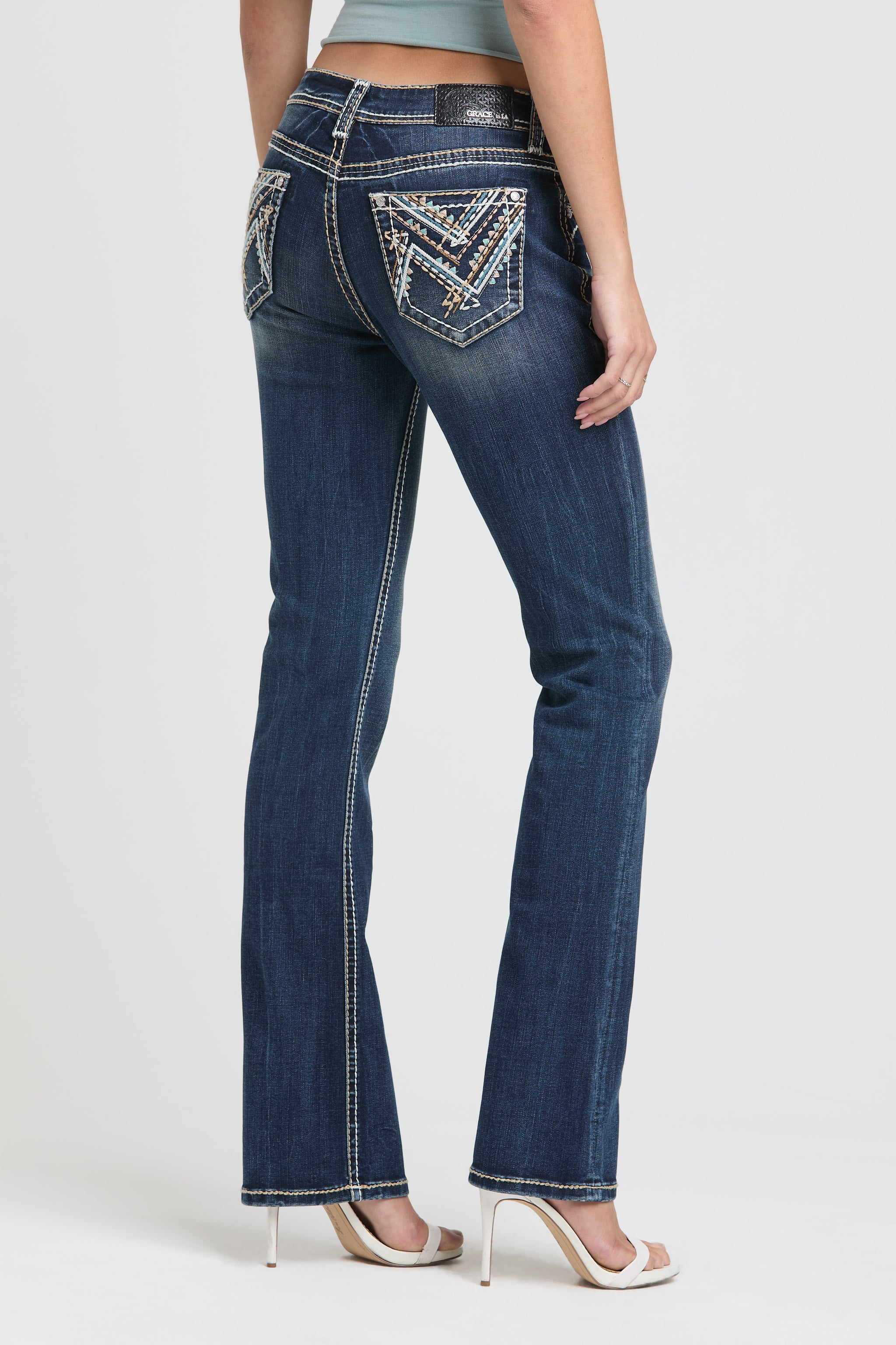 Womens bootcut jeans Full-length angled back view of Grace in LA featuring colorful Aztec-inspired pocket embroidery.