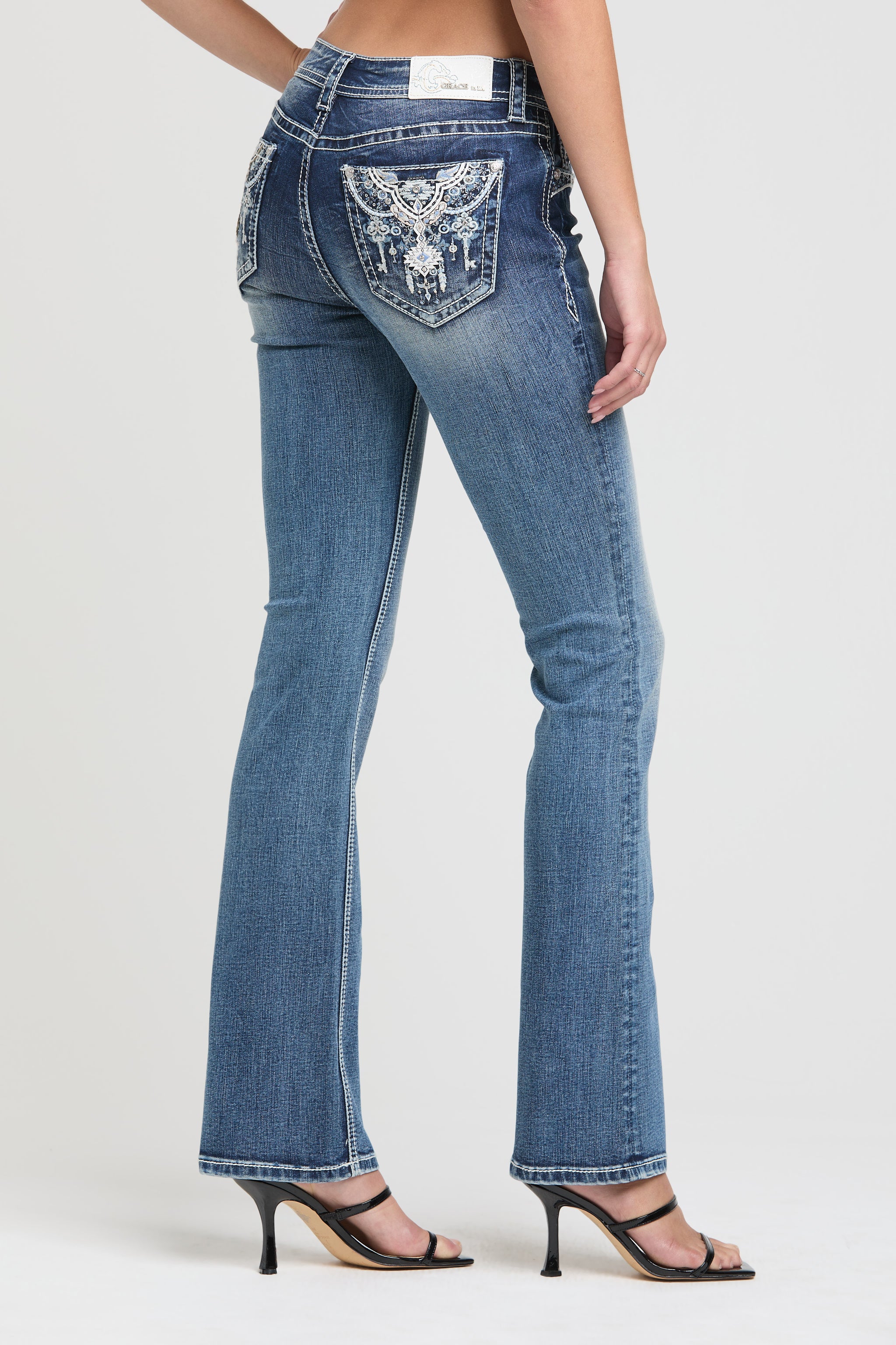 Grace in LA embroidered jeans women featuring a western longhorn bull skull with white floral details and metallic silver stitching on the back pocket.