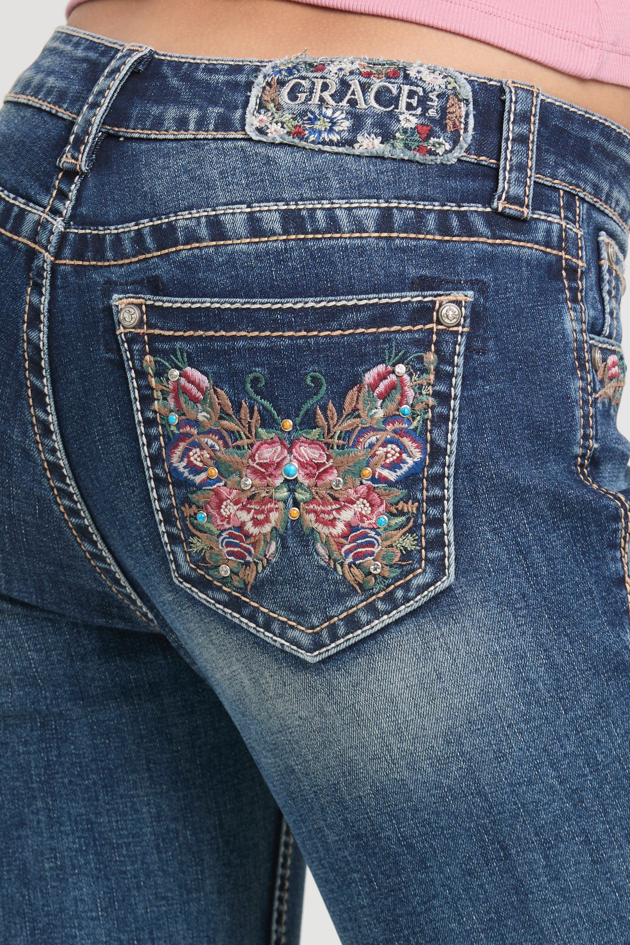 Womens bootcut jeans Close-up of a colorful embroidered butterfly back pocket on Grace in LA.