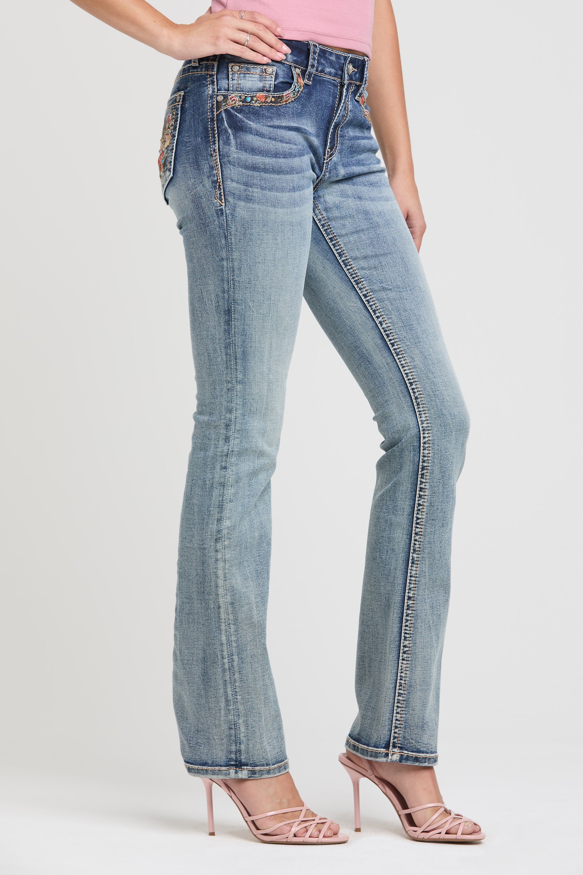 Grace in LA womens bootcut jeans in a featuring a slim fit silhouette, white contrast stitching on the side seams, and styled with pink strappy heels.