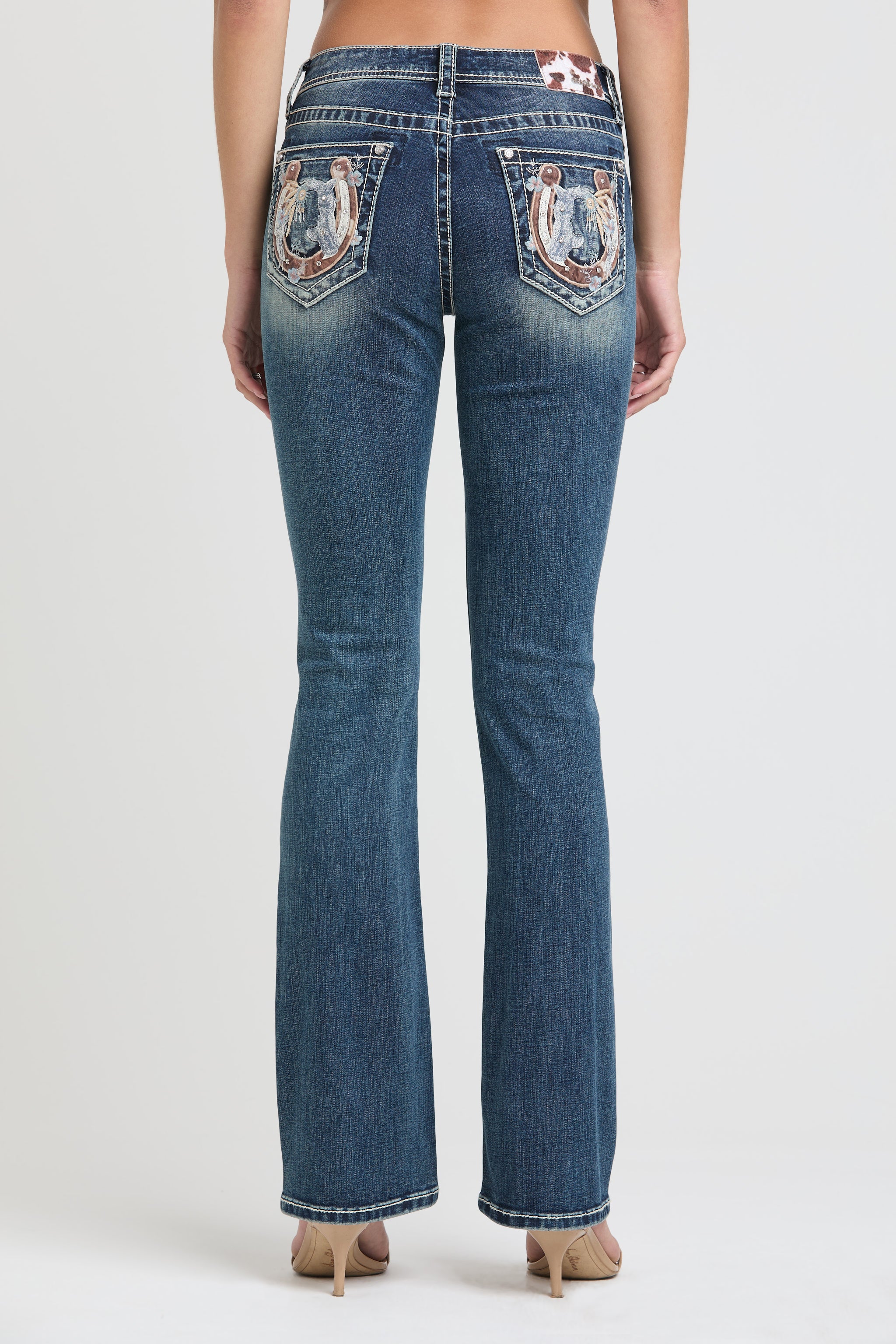 Grace in LA womens bootcut jeans featuring a full rear view of symmetrical embroidered horseshoes, desert landscapes, and floral motifs on both back pockets.