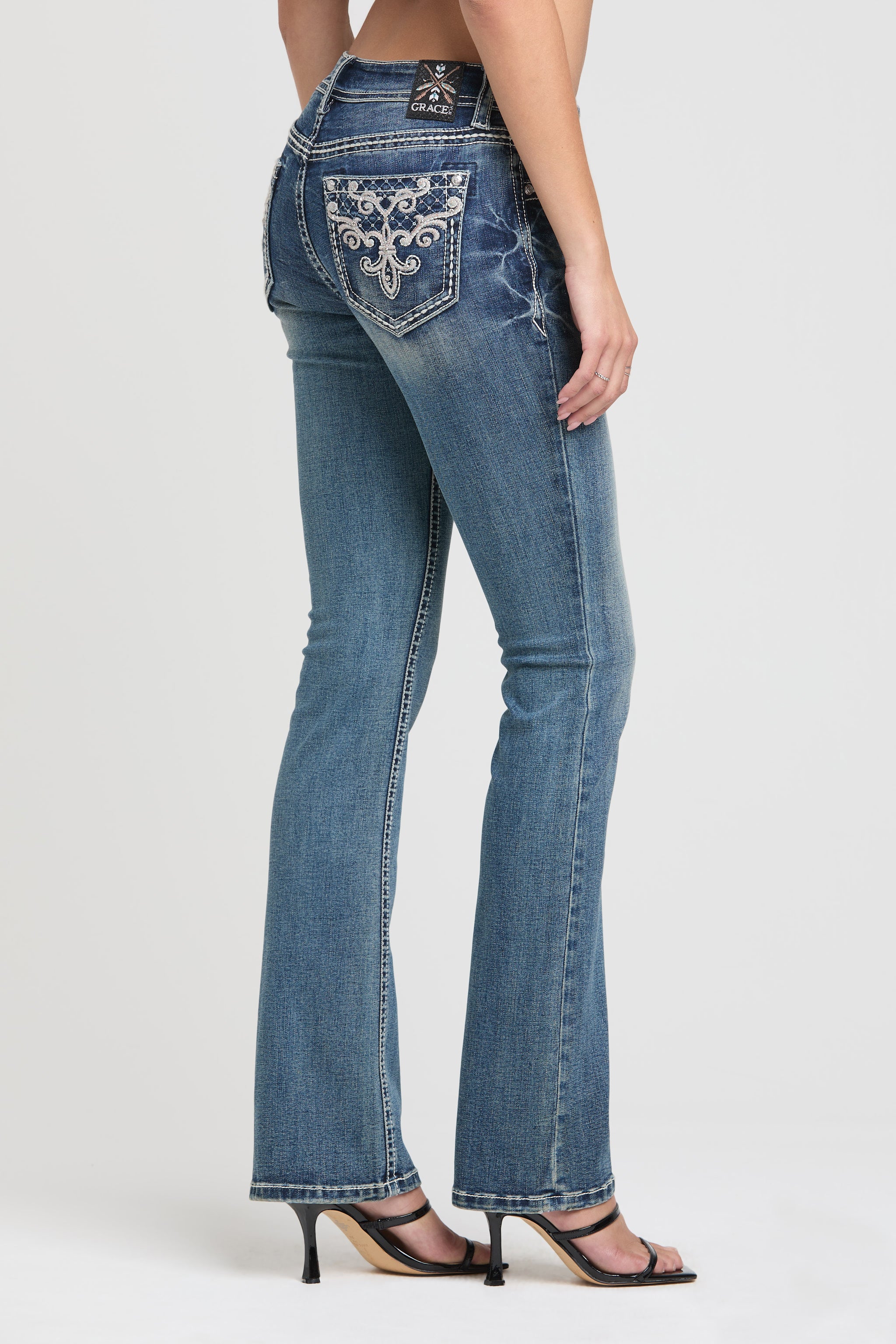 Side back angle of cowgirl jeans women from Grace in LA highlighting intricate silver embroidery.