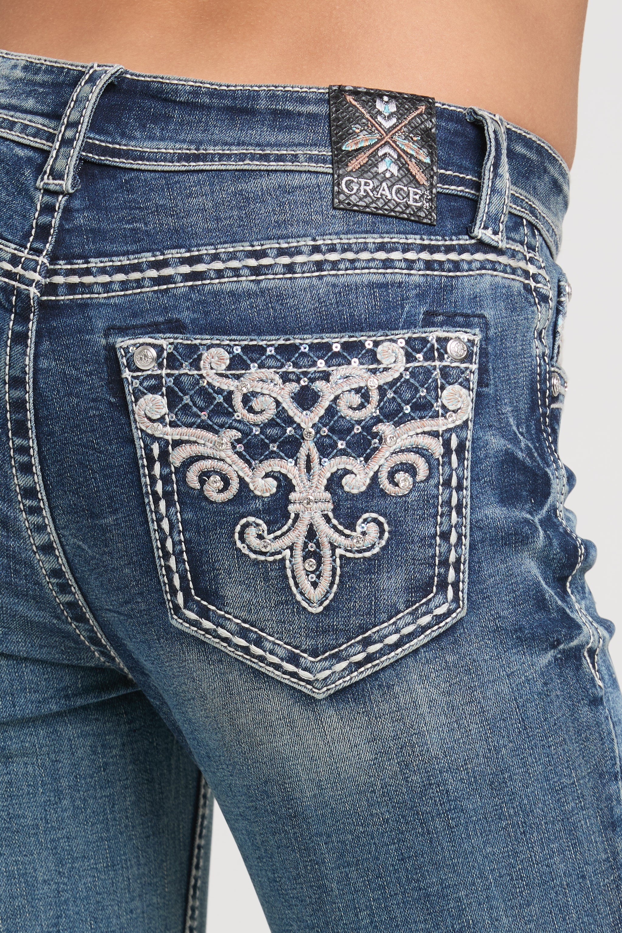 Close-up of decorative fleur-de-lis back pocket on Grace in LA bedazzled jeans women.