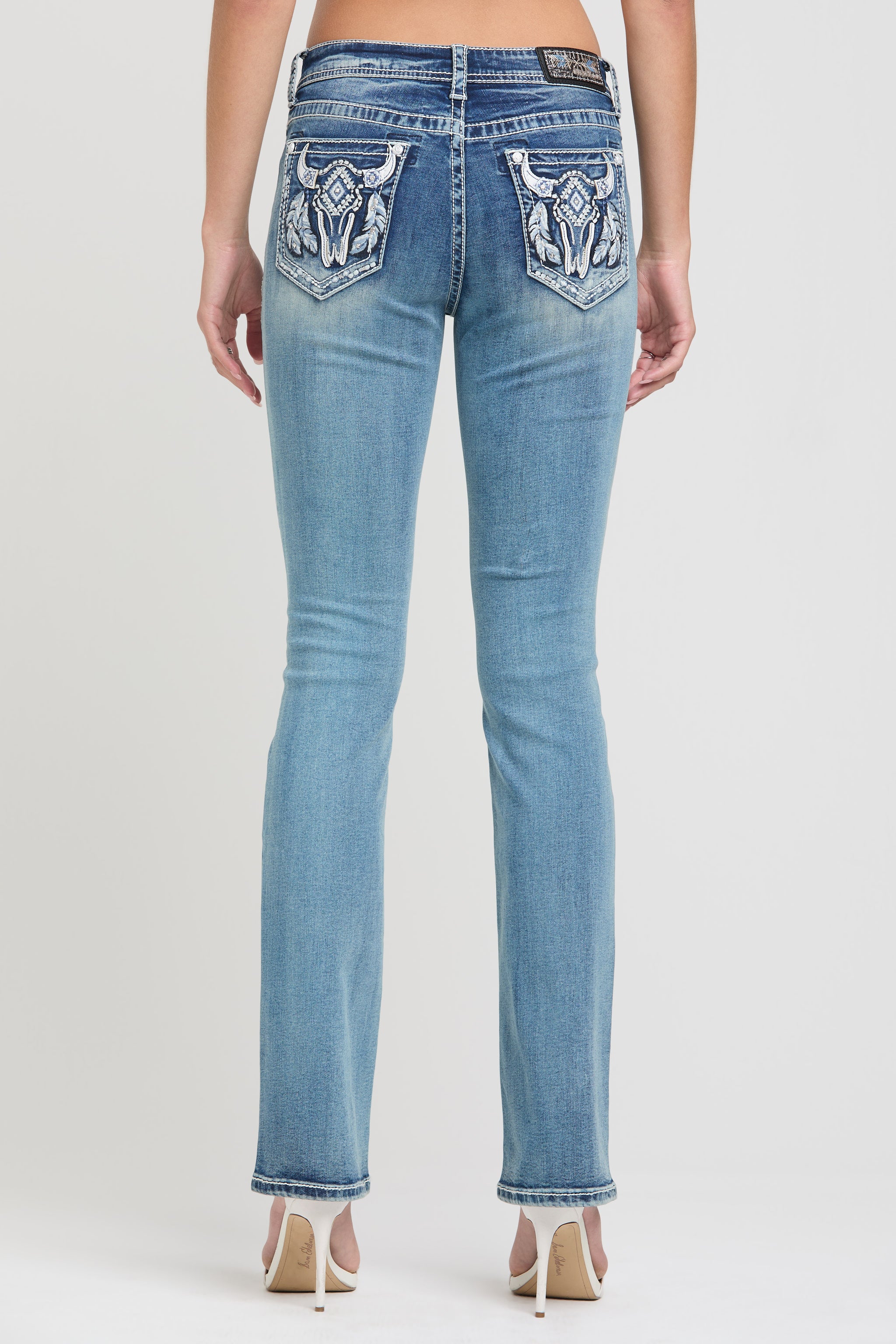 Grace in LA rhinestone jeans for women featuring white tribal-style embroidered back pockets with crystal embellishments.