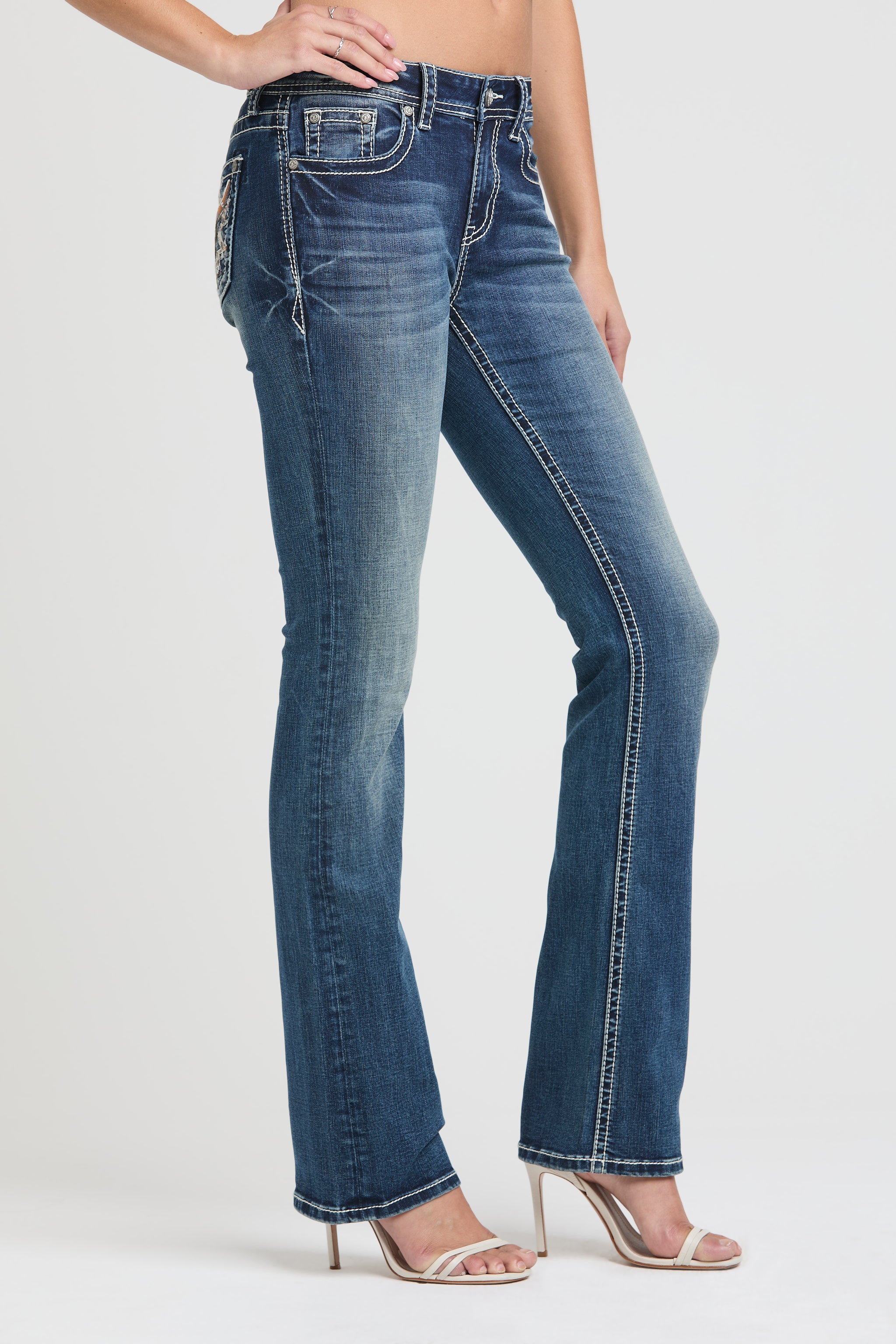 Grace in LA embroidered jeans women featuring a western longhorn bull skull with orange horns and an intricate geometric tribal sunburst on the back pocket.