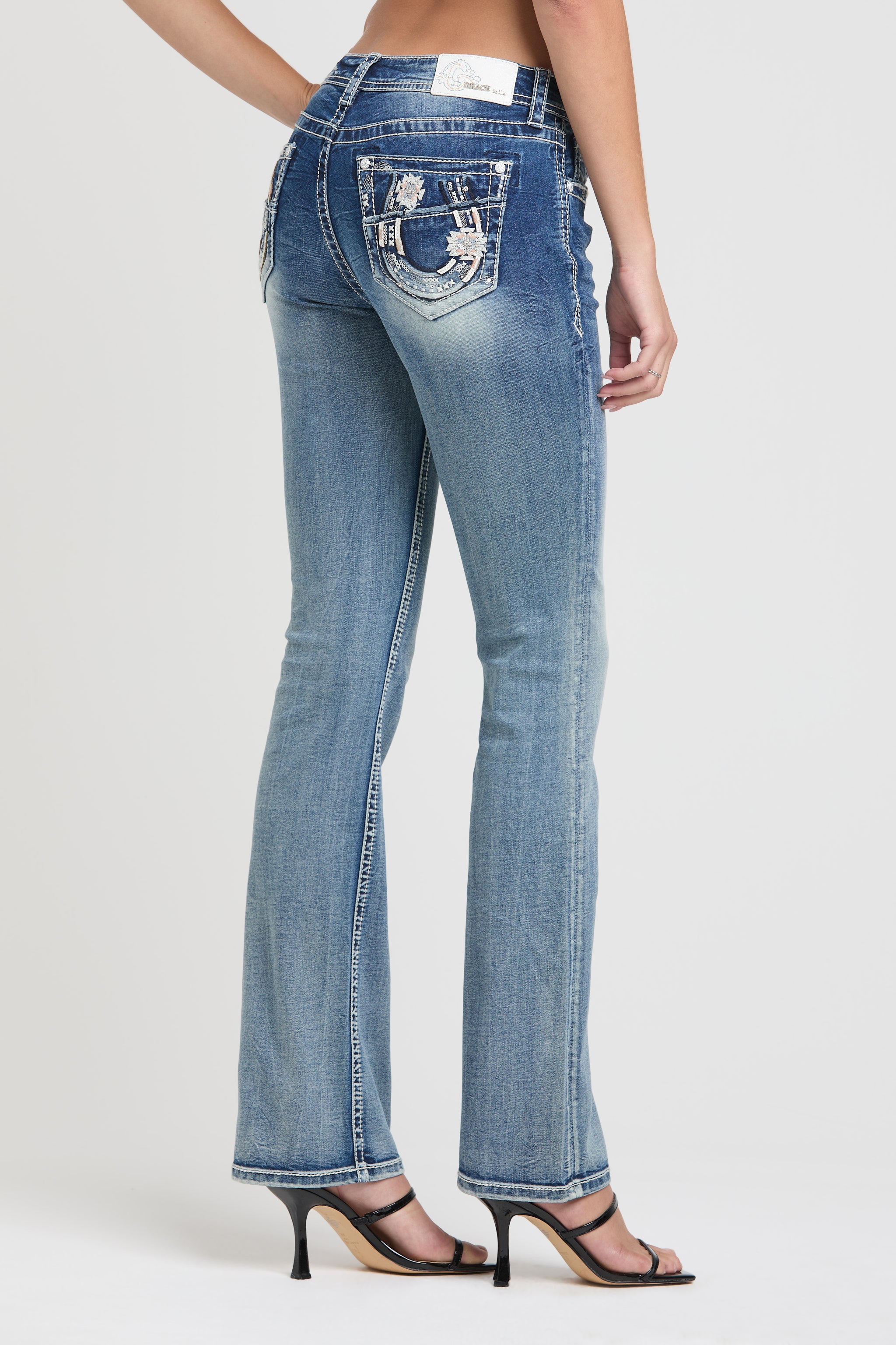 Grace in LA embroidered jeans women featuring a metallic silver horseshoe motif on the back pocket with intricate geometric star patterns and white western stitching.