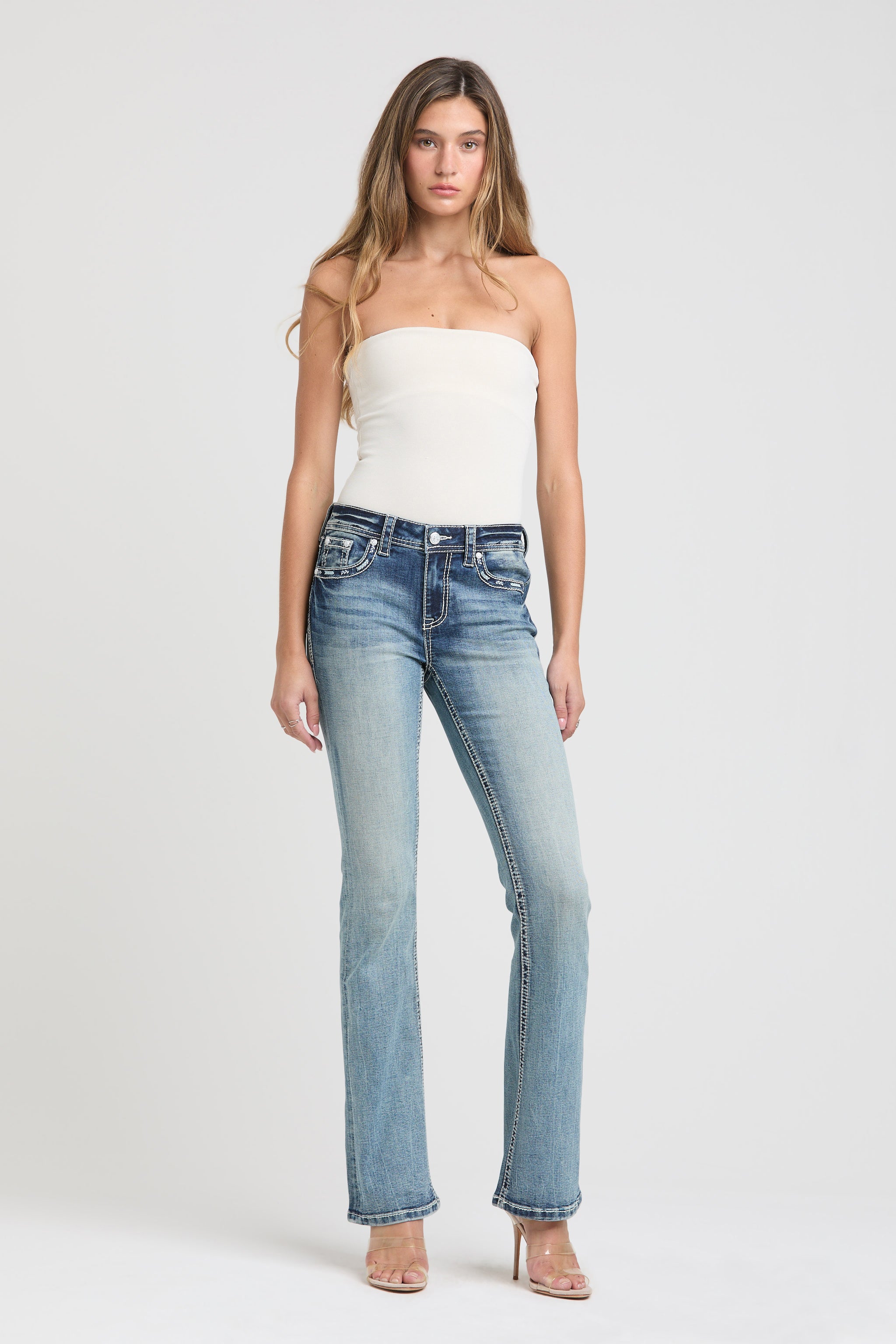 Full-length front view of Grace in LA womens bootcut jeans paired with a white strapless top.