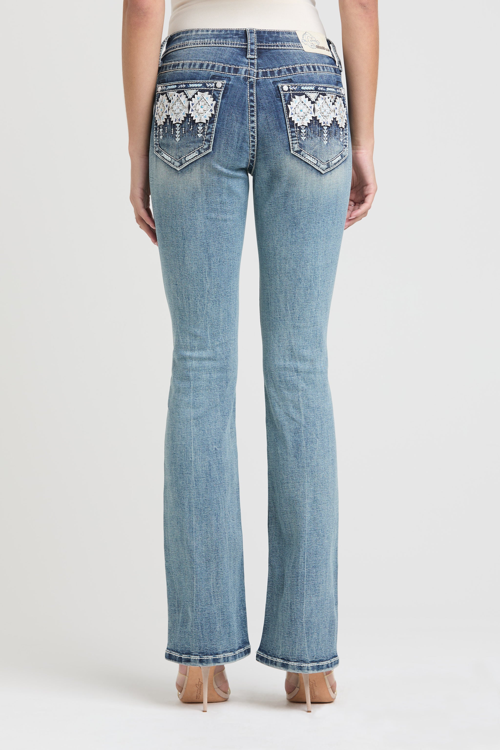 Full back view of Grace in LA low rise jeans women featuring symmetrical white floral pocket embroidery.