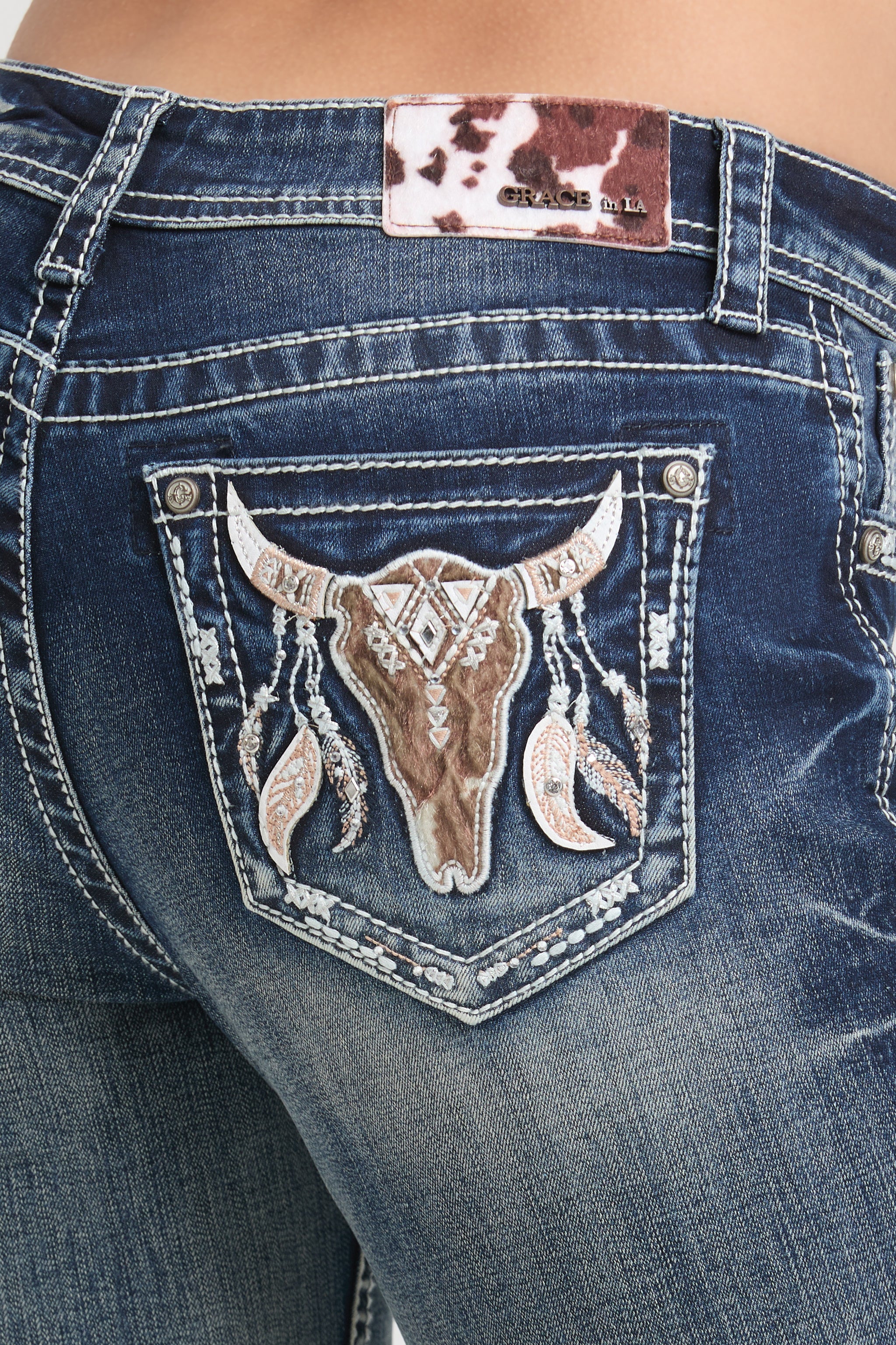Grace in LA Women's Western Jeans - Close-up of Back Pocket with Bull Skull and Feather Embroidery and Cowhide Brand Patch