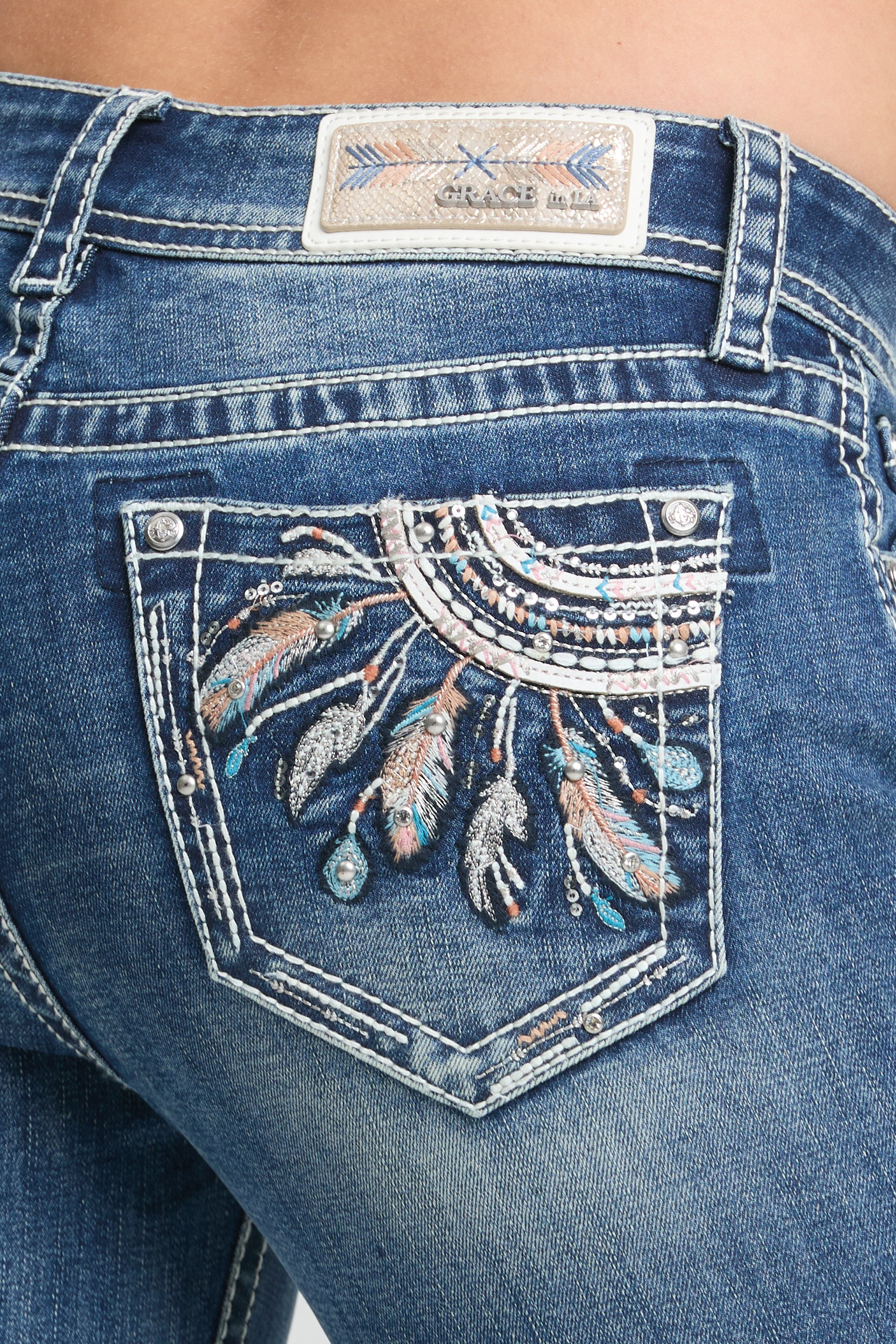 Grace in LA women’s medium wash bootcut jeans with feather embroidered back pocket detail close up