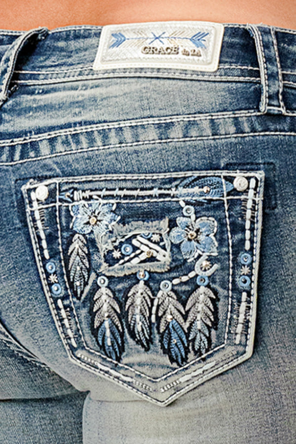 Grace in LA embroidered jeans women featuring a light blue floral and feathered dreamcatcher design on the back pocket and a branded arrow motif waist patch.