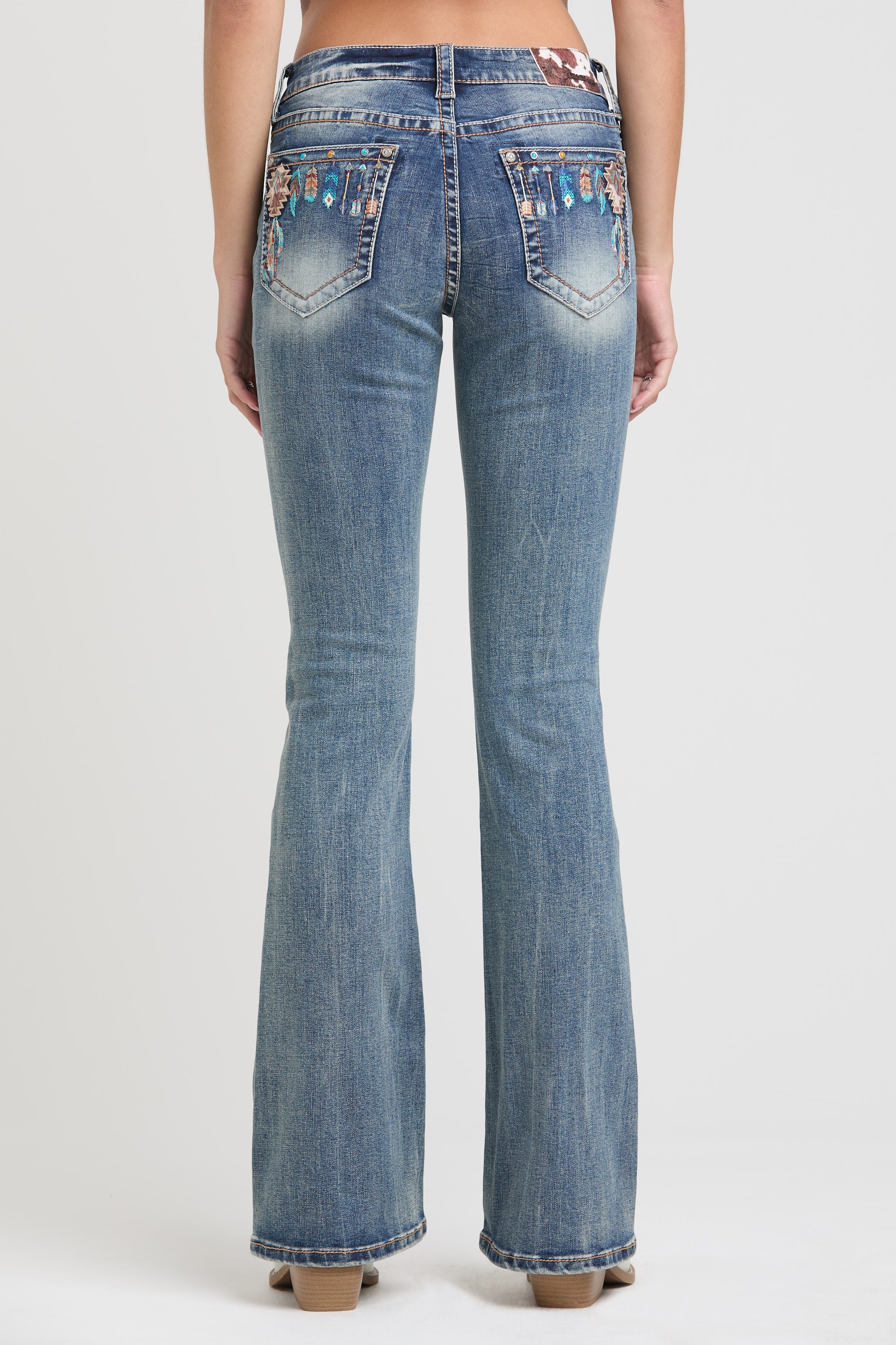 Grace in LA rhinestone jeans for women featuring colorful tribal embroidery and crystal accents on the back pockets of dark wash denim.