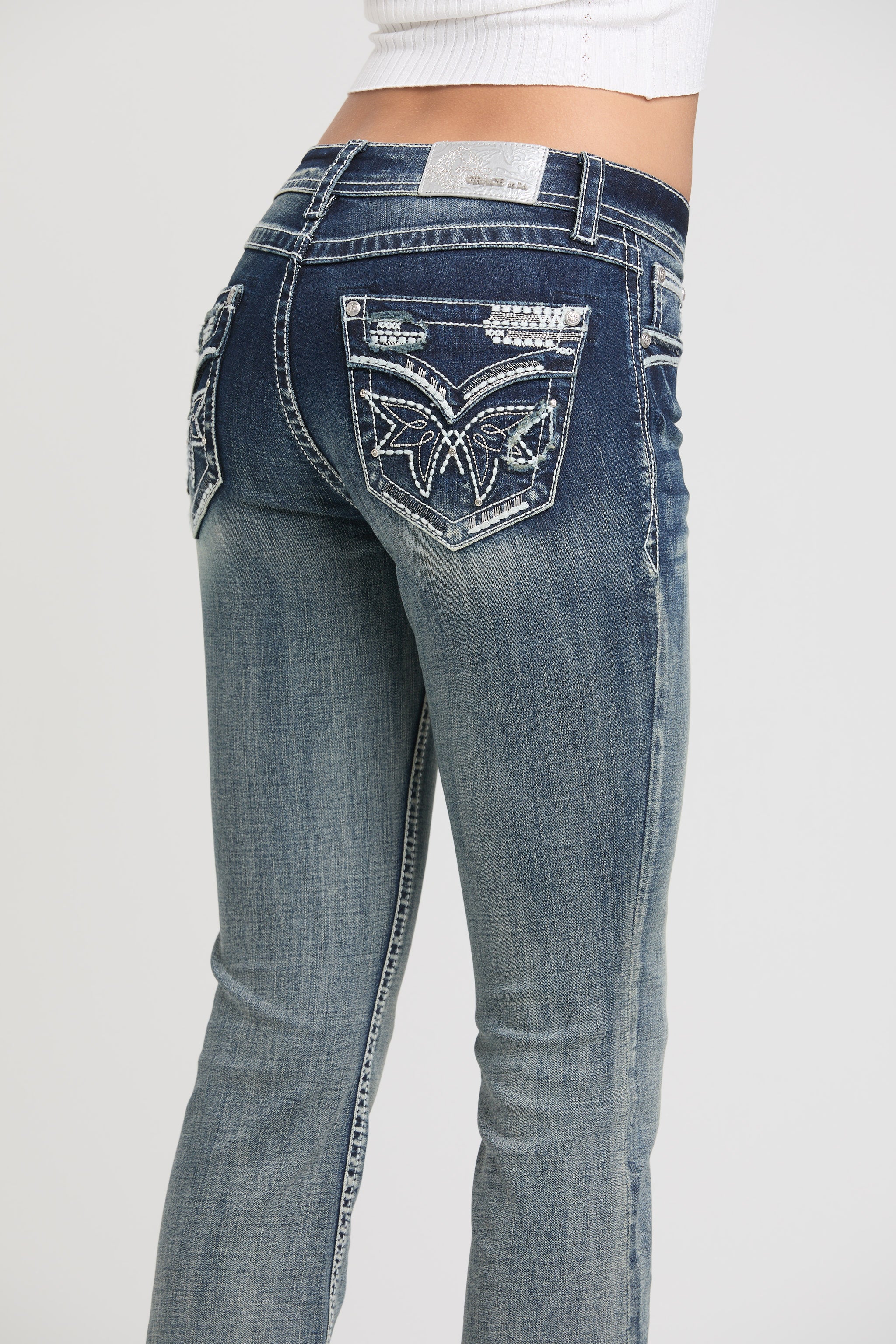 Grace in LA women's acid wash jeans featuring a bootcut fit and elaborate silver metallic wing embroidery on the back pockets.