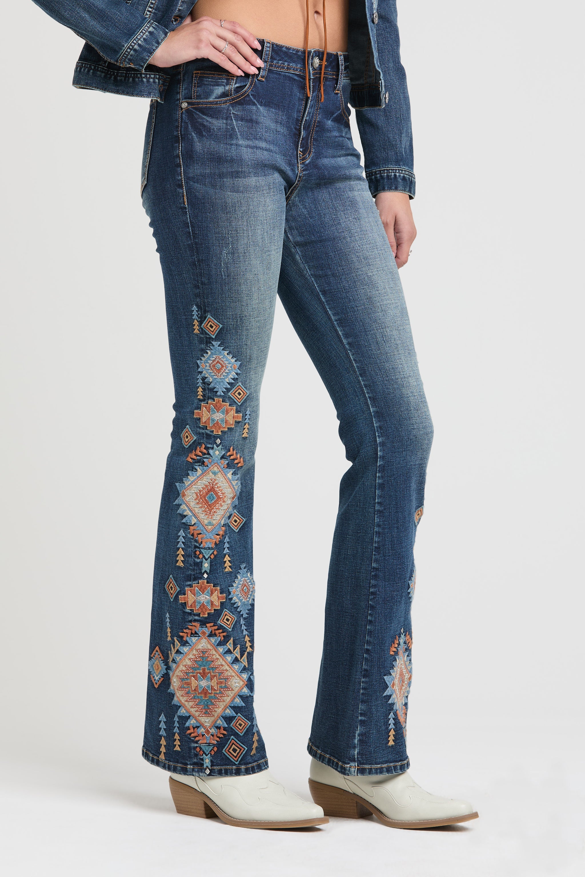 Grace in LA flare jeans for women with a vertical orange and blue geometric tribal embroidery design on the lower leg.
