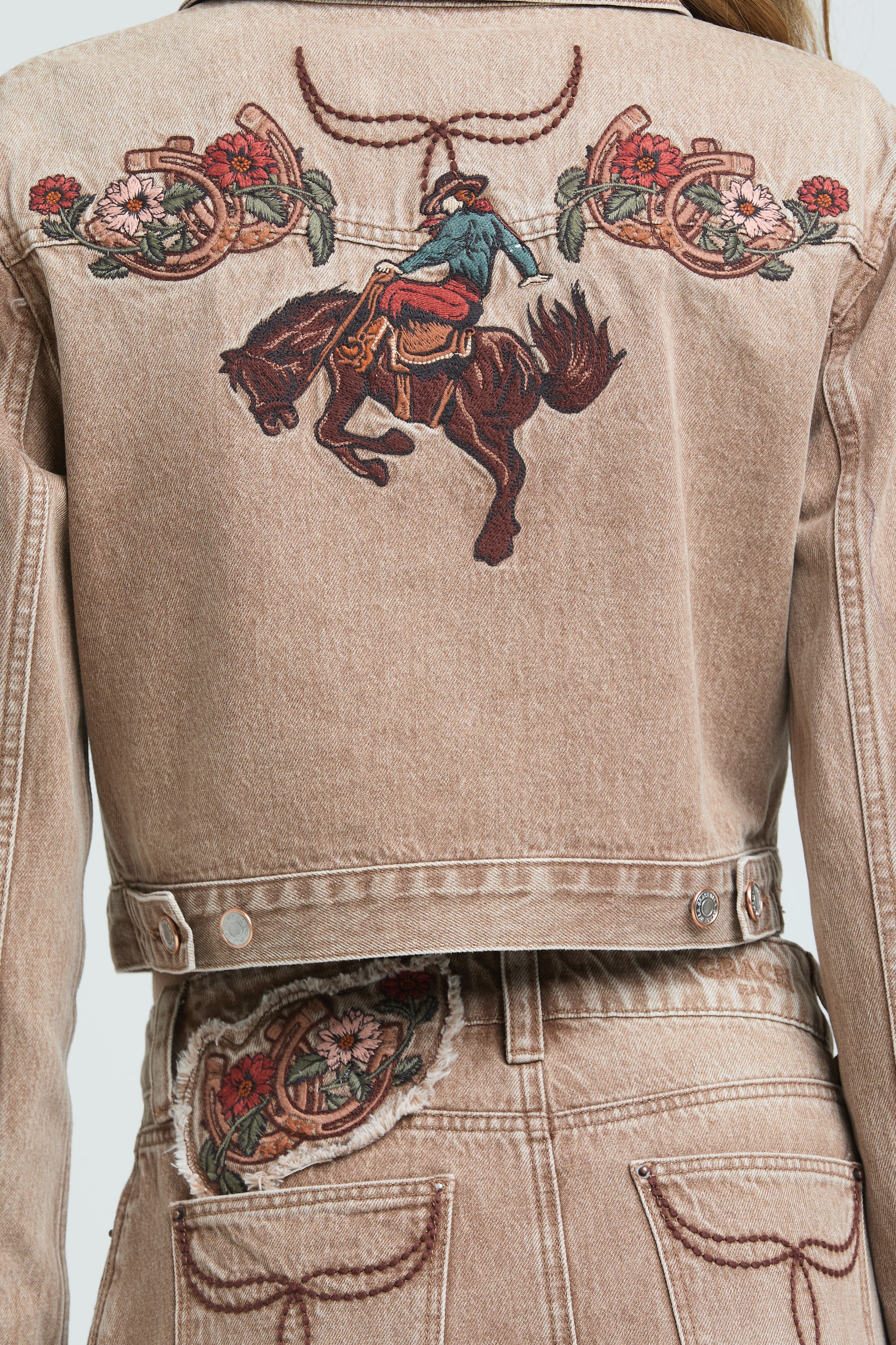 Grace in LA western denim jacket featuring a large cowboy on a bucking horse embroidery with floral accents.