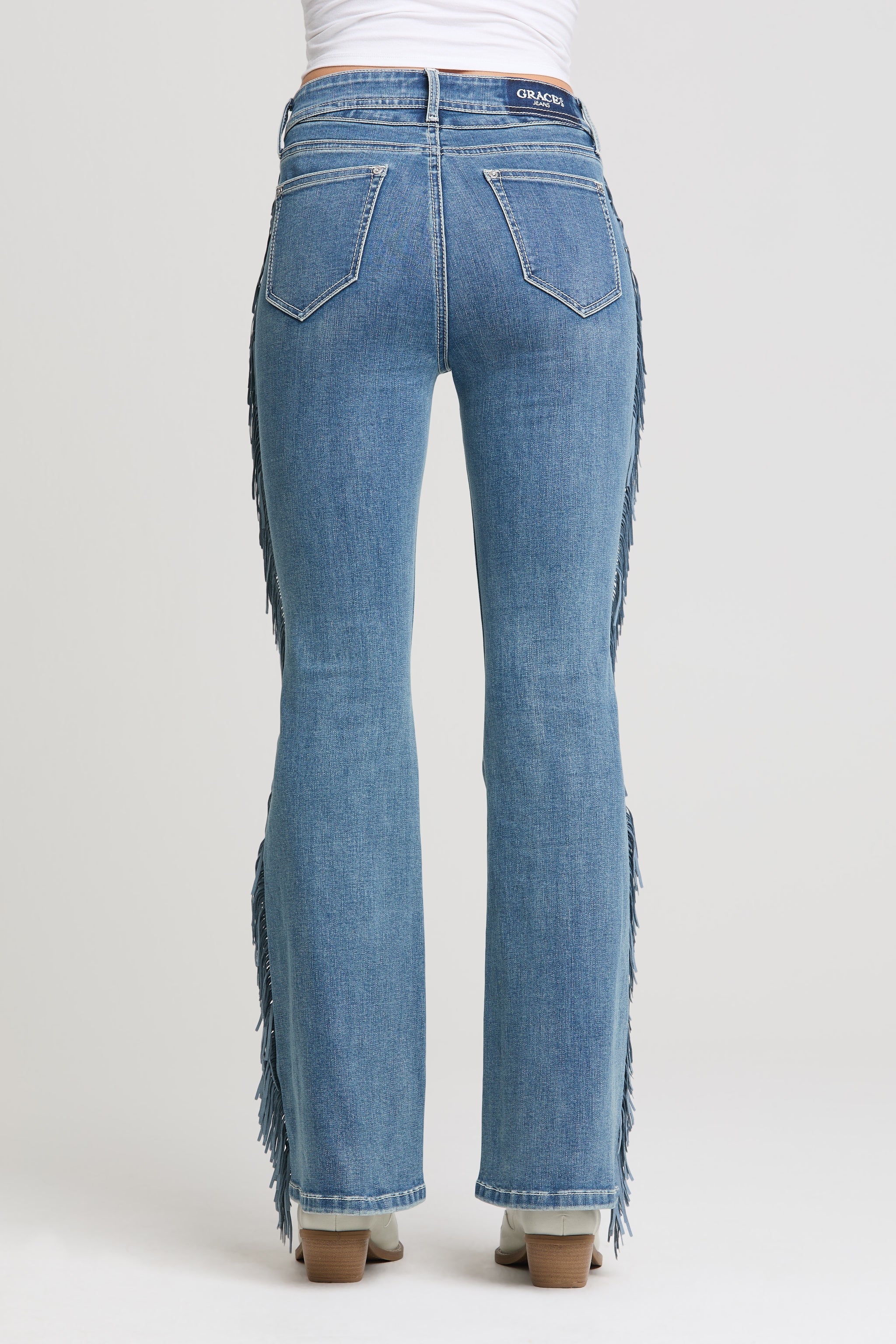 Grace in LA women’s medium wash flare jeans with fringe detail back view
