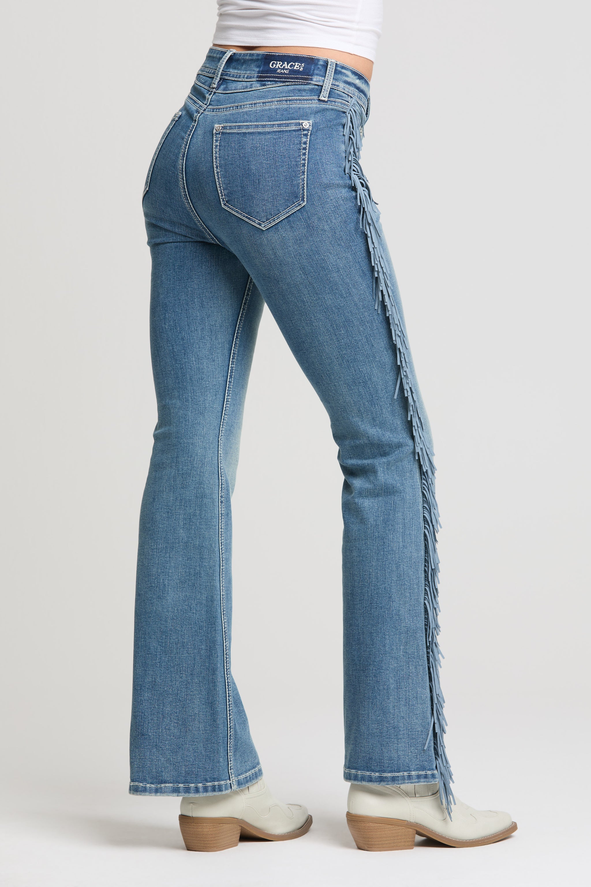 Grace in LA women’s medium wash flare jeans with long side fringe detail back view