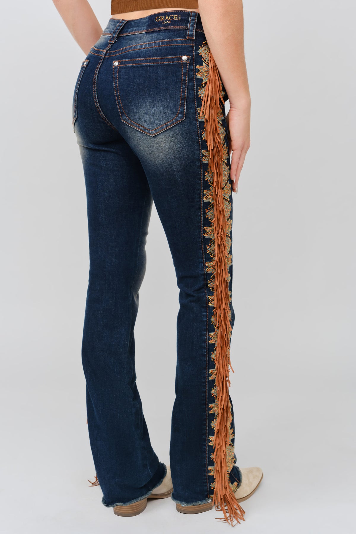 Grace in LA dark wash bootcut jeans side seam detail showing cognac suede fringe