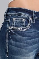Grace in LA bootcut jeans close-up of wing embroidery and rhinestone detailing on medium wash denim