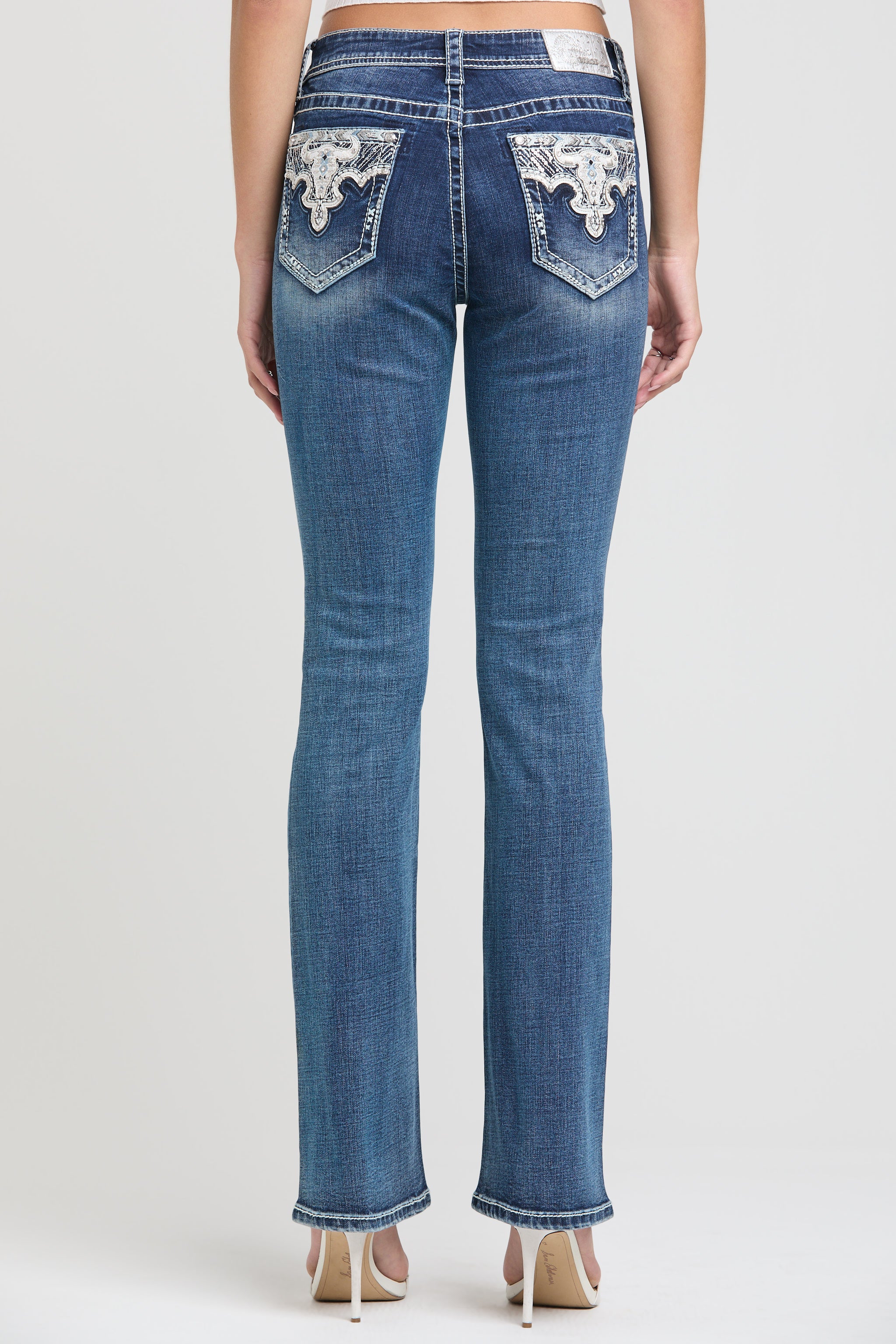 Grace in LA womens bootcut jeans in a medium featuring western-inspired white lace fleur-de-lis embroidery and rhinestone accents on the back pockets.
