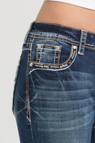 Grace in LA rhinestone jeans for women featuring orange and blue geometric tribal embroidery on the front coin pocket.