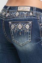 Grace in LA rhinestone jeans for women featuring a dark wash with colorful geometric tribal embroidery and crystal accents on the back pocket.