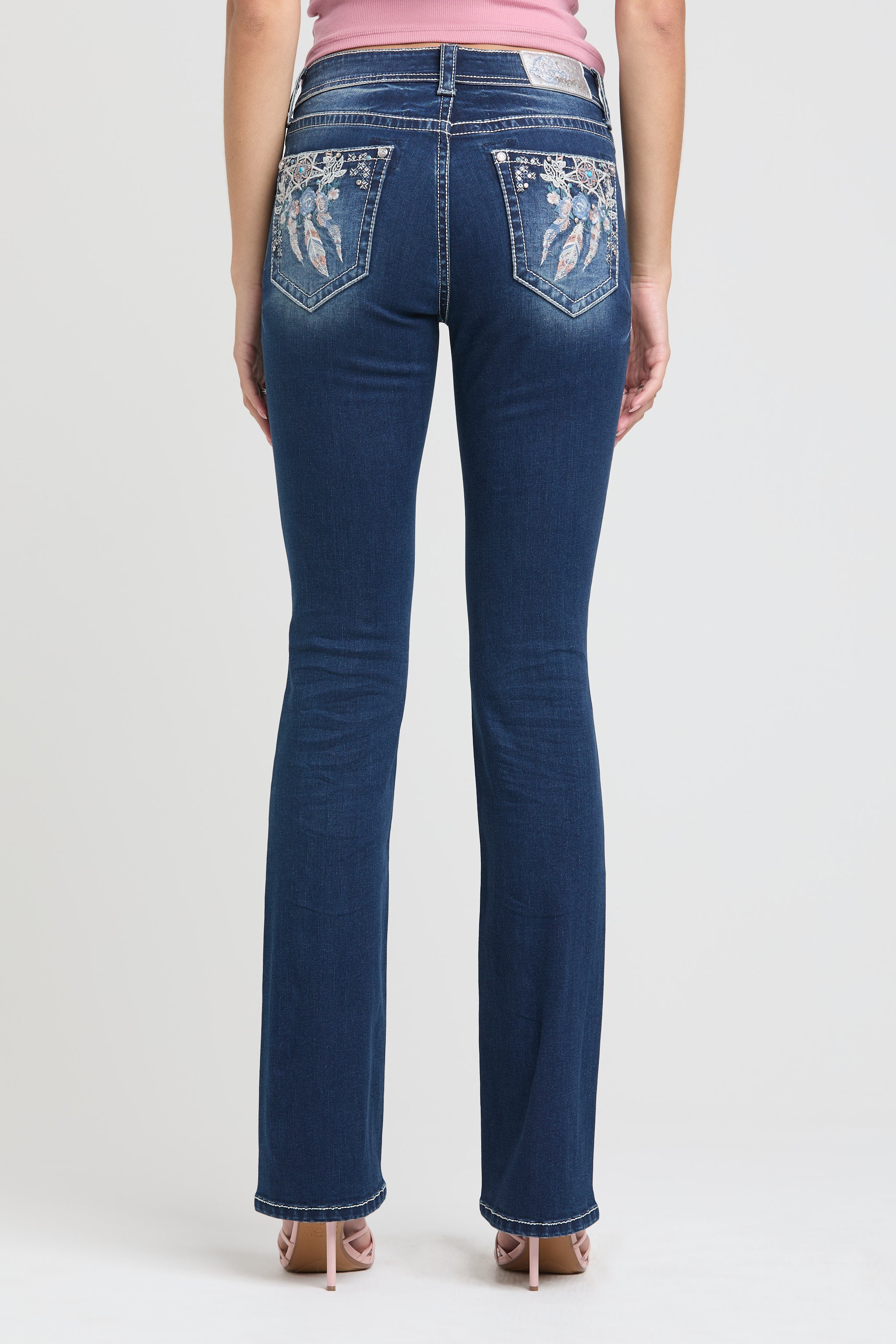 Grace in LA embroidered jeans women featuring a western wing motif with metallic silver stitching and vibrant blue rhinestone accents on the back pocket.