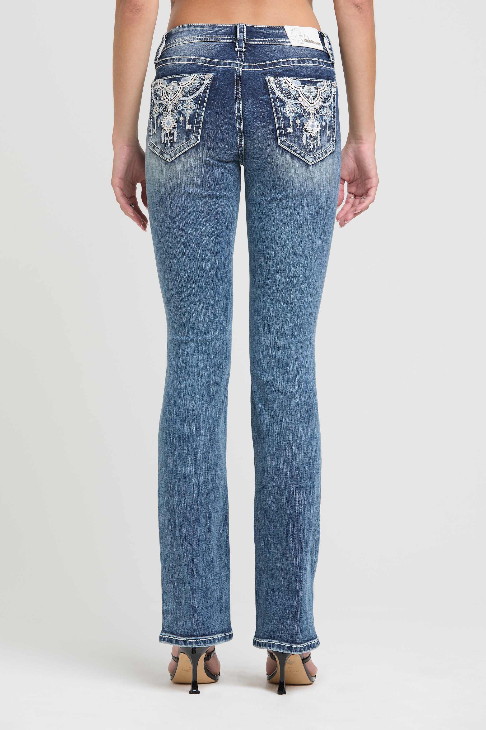 Grace in LA embroidered jeans women featuring a western steer skull motif on the back pocket with vibrant blue and copper metallic stitching.