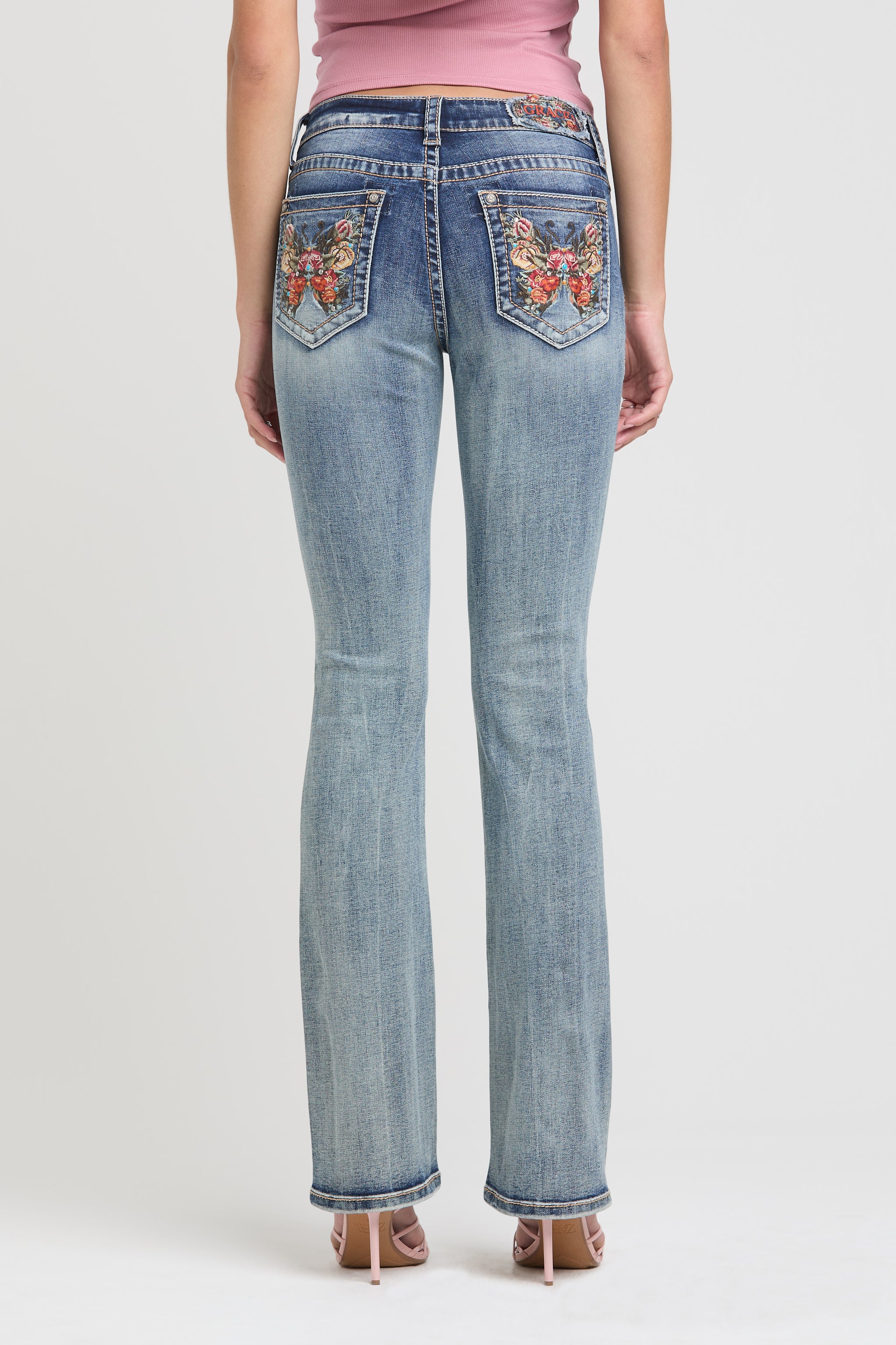 Grace in LA womens bootcut jeans in a light featuring a full rear view with symmetrical orange and red butterfly embroidery on both back pockets.