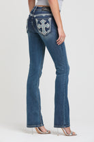 Grace in LA womens bootcut jeans in a dark wash featuring a full rear-view silhouette with ornate white embroidered crosses and turquoise accents on the pockets.