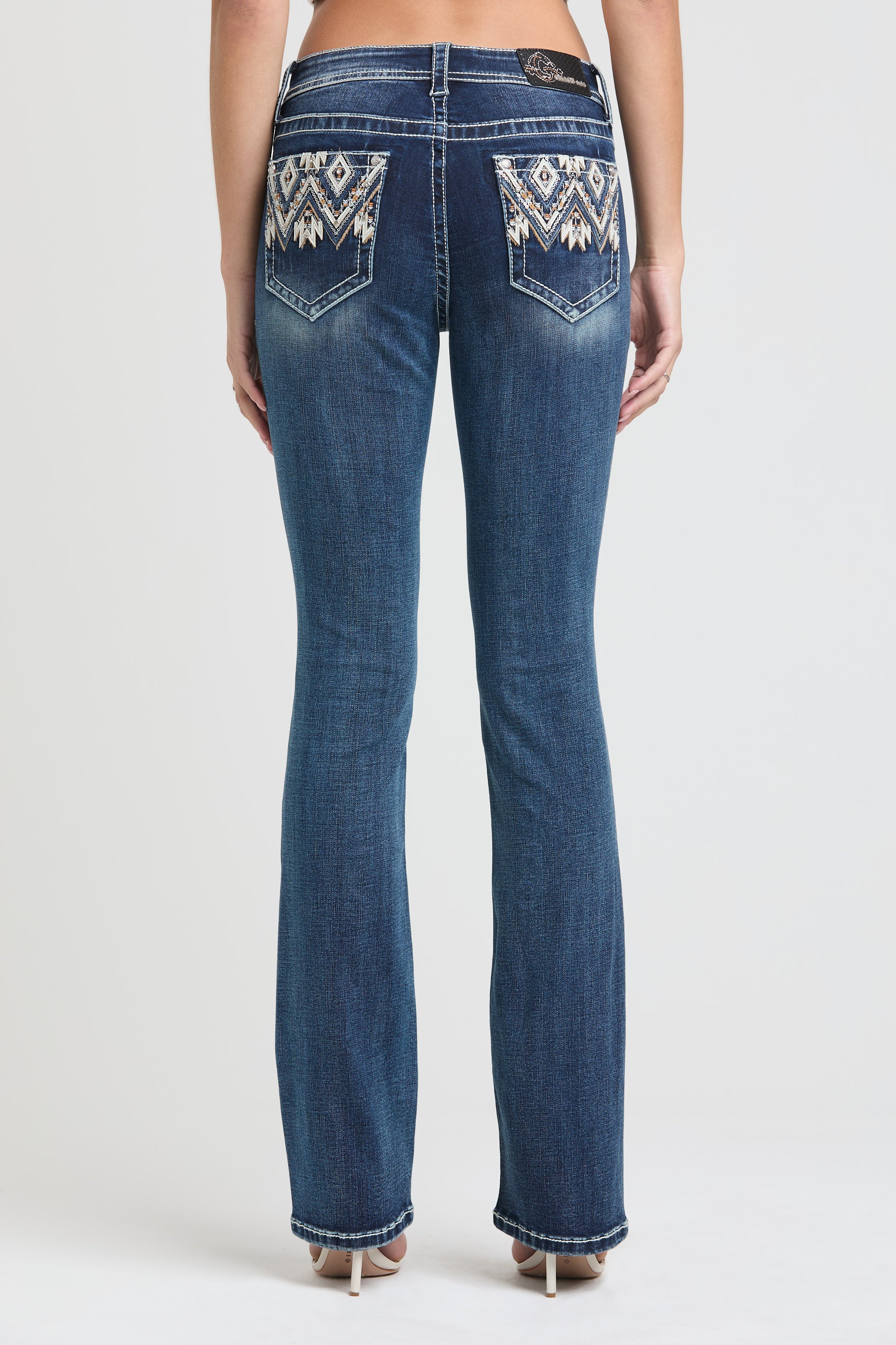 Grace in LA womens bootcut jeans in a dark featuring western-inspired cream and tan geometric tribal embroidery with rhinestone accents on the back pockets.