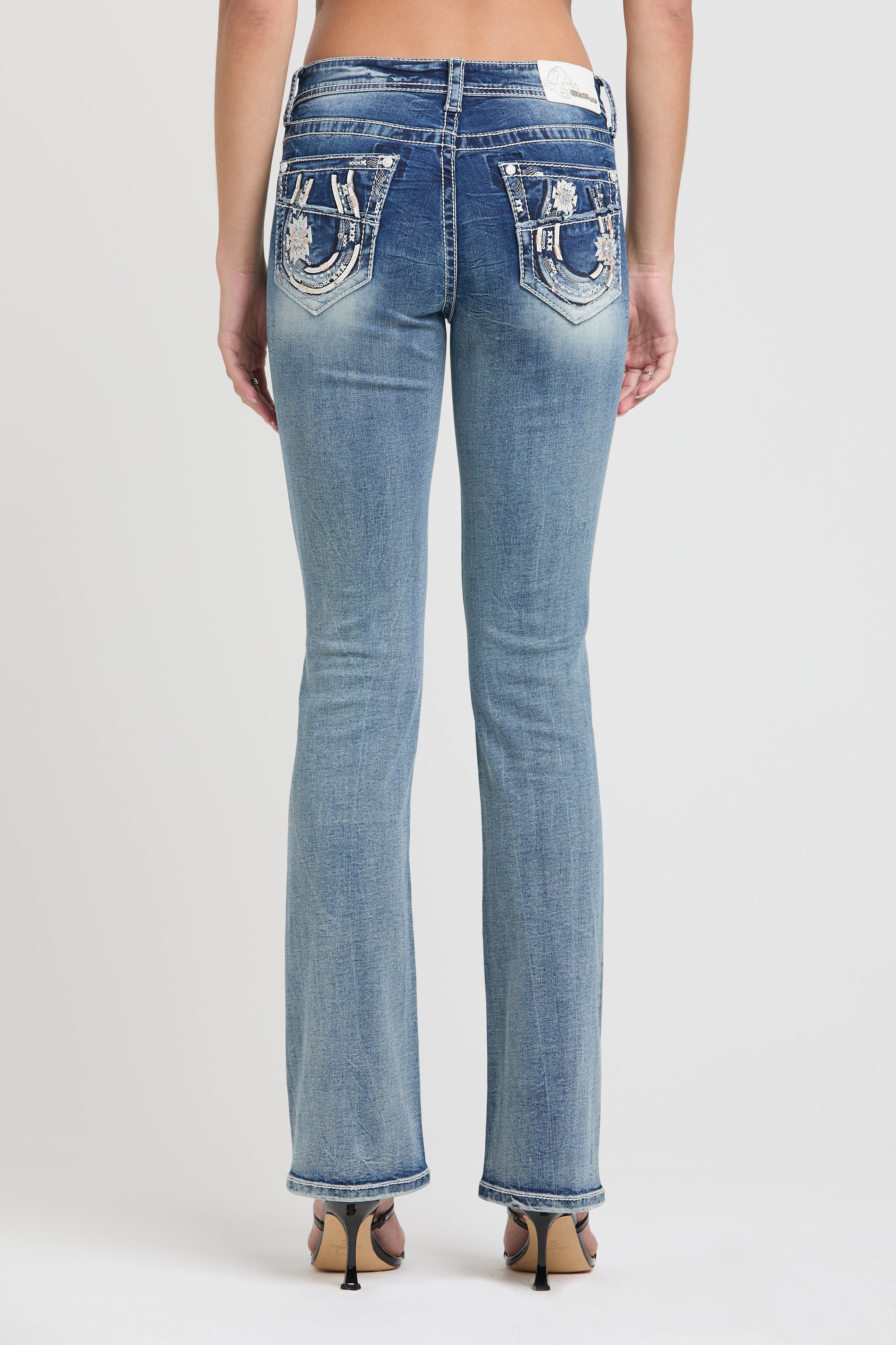 Grace in LA womens bootcut jeans in a light acid wash featuring frayed denim brand initials on the back pockets with rhinestone accents.