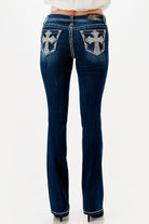 Grace in LA womens bootcut jeans featuring large silver rhinestone cross designs and crystal embellishments on the back pockets.