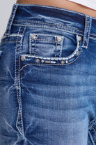Close-up of the front pocket of blue denim jeans with silver metal rivets and contrast stitching, showing the fabric texture and wash details.