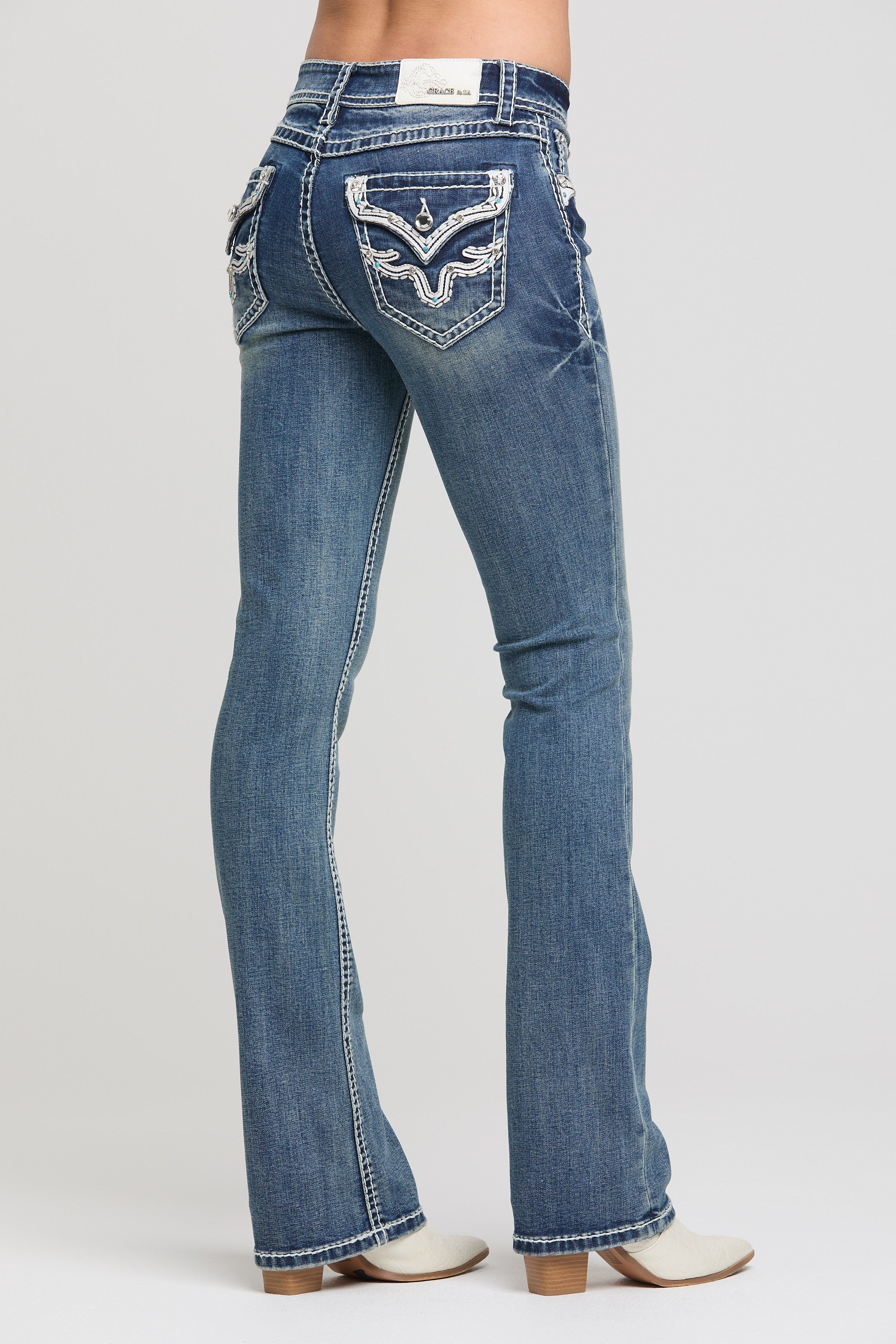 Grace in LA women's medium wash bootcut jeans, side-facing view showing the fitted hip and bootcut leg