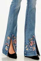 Grace in LA womens flare jeans featuring a split hem with vibrant pink and blue floral embroidery on light denim.