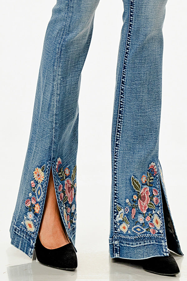 Grace in LA womens flare jeans featuring a split hem with vibrant pink and blue floral embroidery on light denim.
