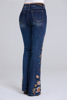 Rear view of dark blue denim flare jeans with floral embroidery down the outer leg, shown on a model against a light gray studio background.