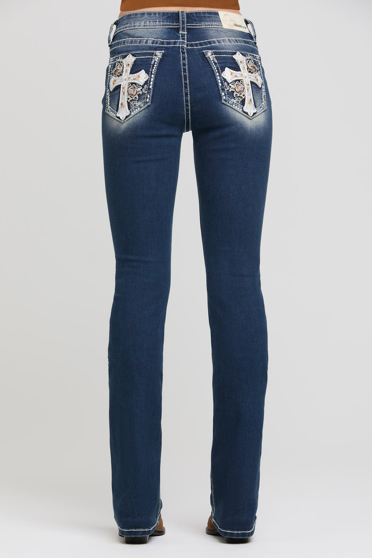 Grace in LA bootcut jeans side view showing cross and floral appliqué placement