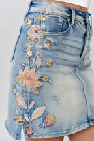 Grace in LA denim skirt close-up of floral colored embroidery on light wash denim